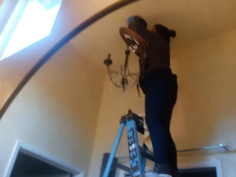 Electrician installing a chandelier in a Jacinto City residence